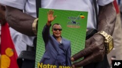  In this Friday March 19, 2021 file photo, a supporter of President Denis Sassou N'Guesso holds his photo during the last rally of the presidential campaign in Brazzaville, Congo. Republic of Congo pressed ahead Sunday March 21, 2021.
