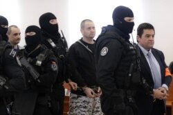 FILE - Suspects in the 2018 slaying of investigative journalist Jan Kuciak and his fiancee, Martina Kusnirova, are escorted by armed police officers from a courtroom in Pezinok, Slovakia, December 19, 2019.