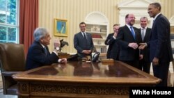 El presidente Barack Obama sonríe al ver al presidente de Chile, Sebastián Piñera sentado en su sillón presidencial. 