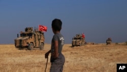 Turkish armored vehicles conduct a joint ground patrol with American forces in the so-called "safe zone" on the Syrian side of the border with Turkey, near the town of Tal Abyad, northeastern Syria, Oct. 4, 2019. 
