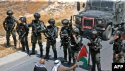 Palestinian protesters sit before Israeli troops during a demonstration against the expropriation of Palestinian land by Israel, in the village of Kafr Malik northeast of Ramallah in the Israeli-occupied West Bank.