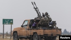 A rebel fighter sits on the back of a vehicle in Homs countryside