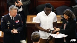 Malian migrant Mamoudou "Spider-Man" Gassama, center, is awarded Paris' Grand Vermeil medal by mayor Anne Hidalgo as the chief of the Paris' fire Brigade General Jean-Claude Gallet, left, applauds at the city council room in Paris, June 4, 2018.