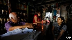 Trabajadores conversan cerca de una vela en un establecimiento durante un apagón en Caracas el 30 de agosto de 2024.