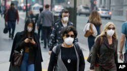 FILE - In this Nov. 9, 2018 file photo, people wear masks while walking through the Financial District in the smoke-filled air in San Francisco.