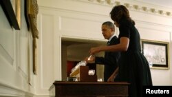 Presiden AS Barack Obama (kiri) dan ibu negara Michelle Obama menyalakan lilin dan mengheningkan cipta sejenak di Gedung Putih, Sabtu (14/12) untuk mengenang para korban tragedi penembakan di SD Sandy Hook setahun yang lalu. 