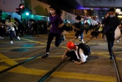 Manifestantes pro democracia en Hong Kong huyen mientras la policía les dispara bombas lacrimógenas.