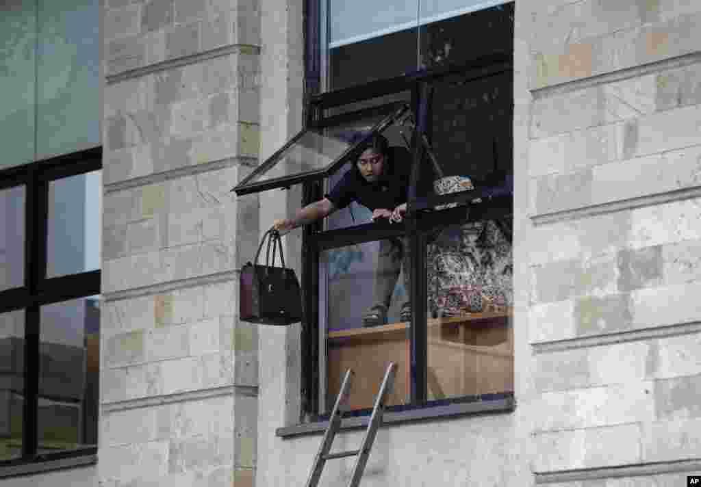 Mwanamke anaejaribu kukimbia akitupa kwanza mkoba wake kabla ya kupita dirishani.