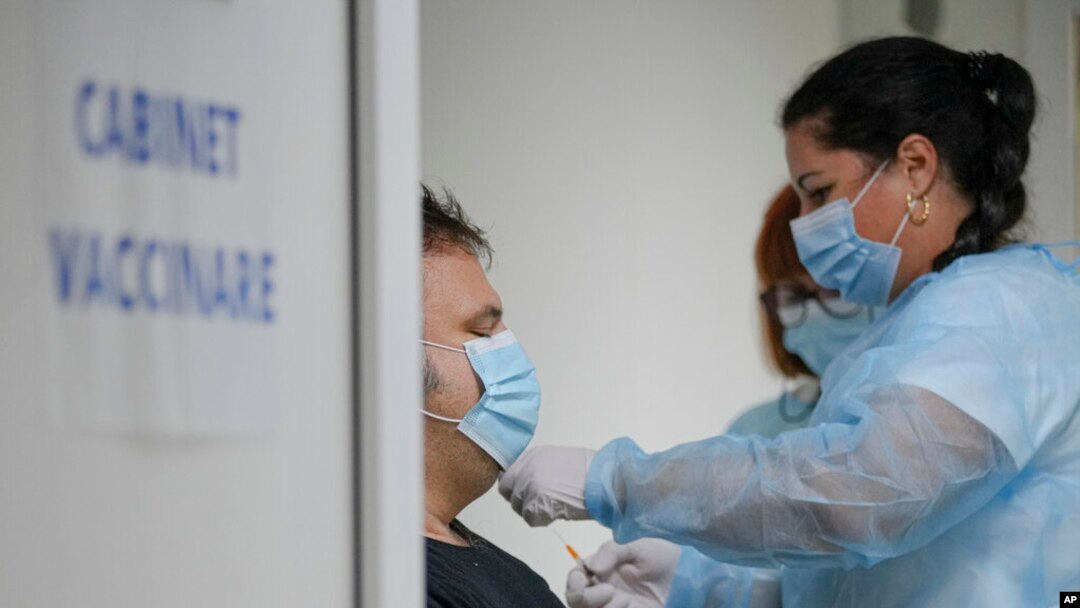 FILE - Medical staff administer the third dose booster Pfizer vaccine shot to a man at the Matei Bals hospital in Bucharest, Romania, Sept. 28, 2021. 