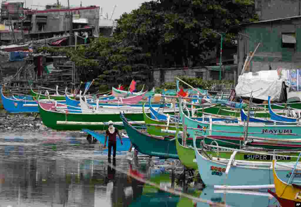 A man walks by docked fishing boats during the start of a lockdown due to a rise in COVID-19 cases in the city of Navotas, Manila, Philippines.
