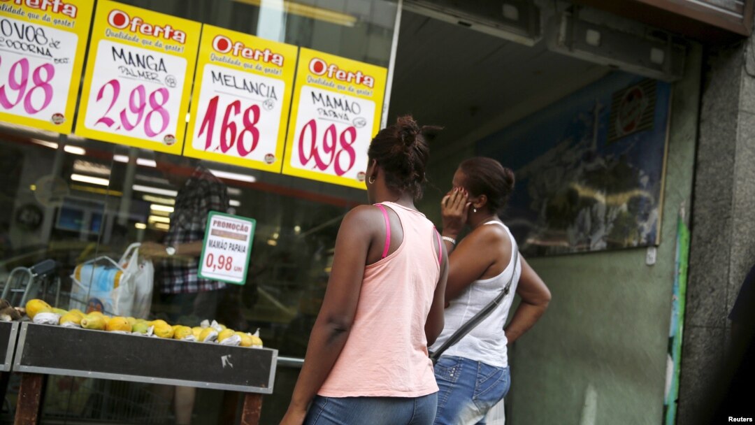 FILE - Women look at prices at a food market in Rio de Janeiro, Brazil, Jan. 21, 2016.