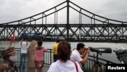 Chinese visitors look on from the Broken Bridge as a train travels on the Friendship Bridge across the Yalu river from North Korea to China, in Dandong, Liaoning province, China, June 10, 2018. 