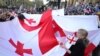 FILE - Demonstrators hold a giant Georgian flag during a rally organized by Georgian opposition parties in support of the country's membership in the European Union, in Tbilisi, Georgia, on April 9, 2023.