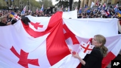 FILE - Demonstrators hold a giant Georgian flag during a rally organized by Georgian opposition parties in support of the country's membership in the European Union, in Tbilisi, Georgia, on April 9, 2023.