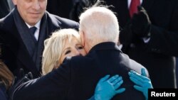 La primera dama de EE. UU., Jill Biden, abraza a su esposo, Joe Biden, el día de la investidura de éste como 46º presidente de la nación, el 20 de enero de 2021. Jill Biden viste guantes fabricados por Wing+Weft Gloves. 