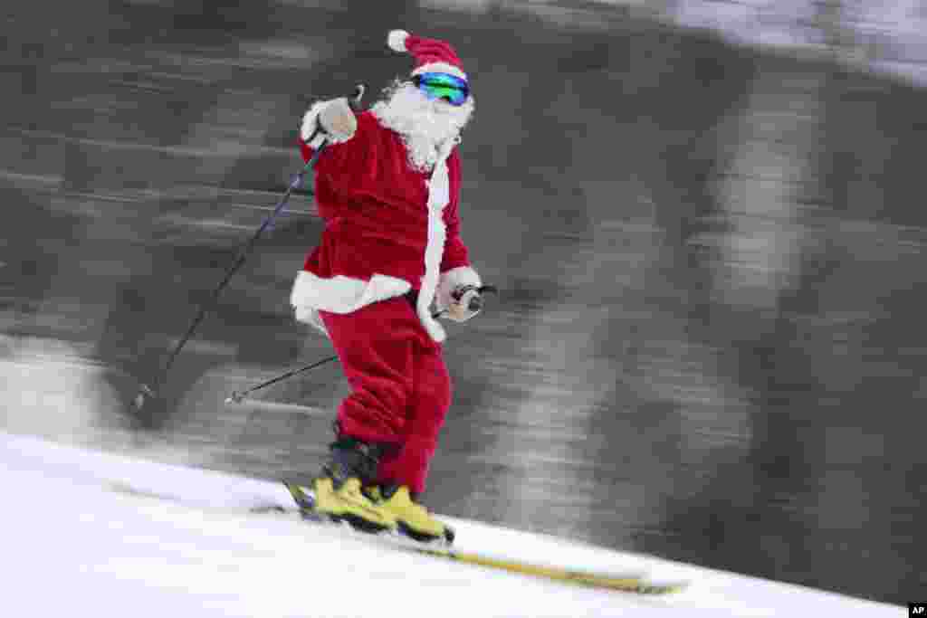 Скијач облечен како Дедо Мраз скија за добротворни цели во скијачкиот центар Сандеј Ривер во Њури, Мејн.