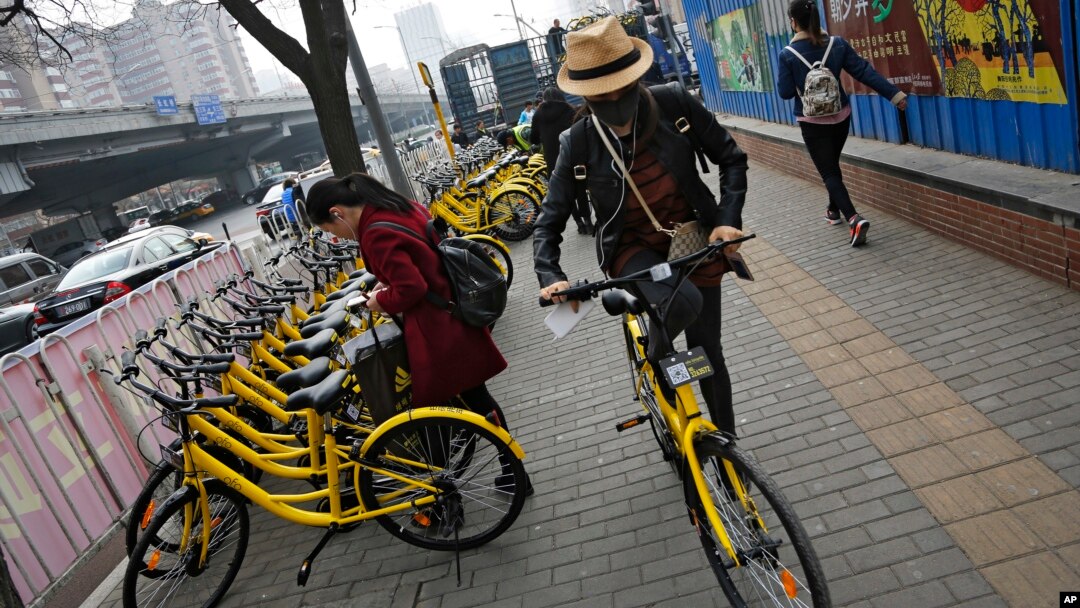 FILE - In this March 21, 2017 photo, commuters use bicycles from bike-sharing company Ofo placed on the sidewalk in Beijing, China. Using shared bikes, thousands of university students rode overnight from Zhengzhou, the largest city in Henan province, to Kaifeng.