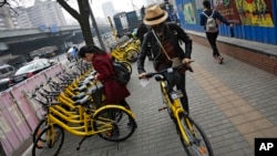 FILE - In this March 21, 2017 photo, commuters use bicycles from bike-sharing company Ofo placed on the sidewalk in Beijing, China. Using shared bikes, thousands of university students rode overnight from Zhengzhou, the largest city in Henan province, to Kaifeng.