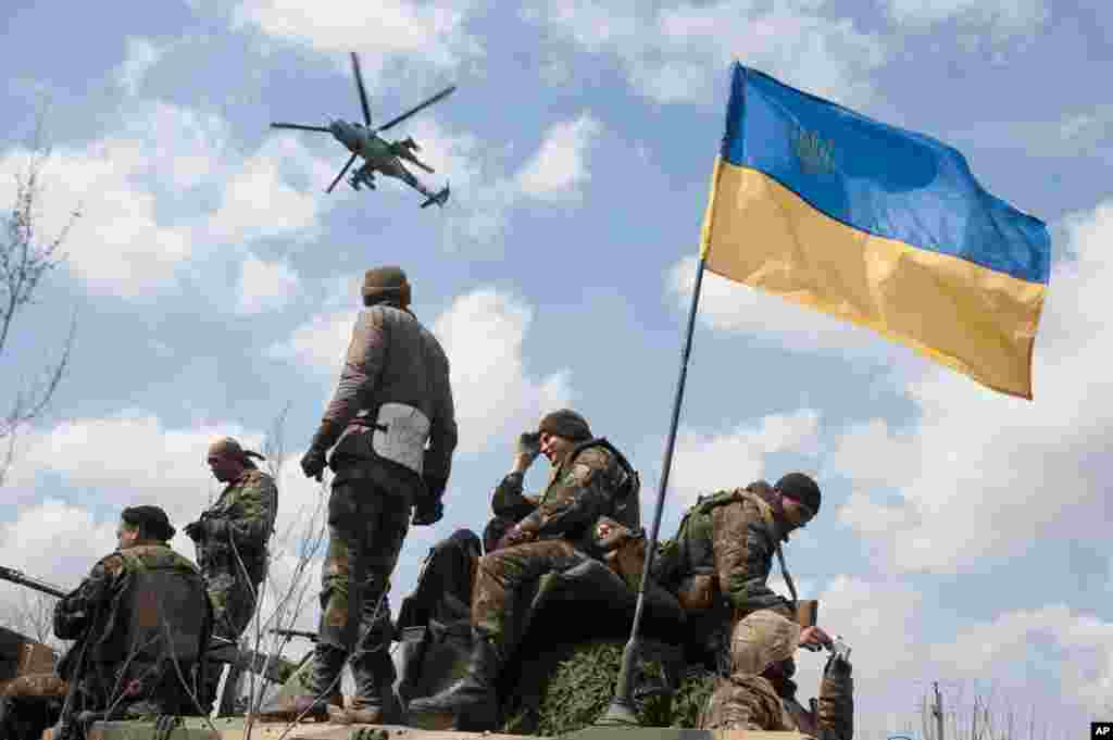 A Ukrainian Army helicopter flies over a column of Ukrainian Army combat vehicles on the way to the town of Kramatorsk, Ukraine, April 16, 2014.