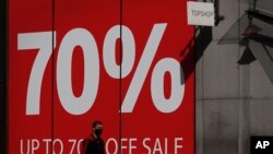 A man wearing a face mask walks past a closed shop advertising a sale, on Oxford Street in London, as the country is in lockdown to help curb the spread of the coronavirus, April 15, 2020.