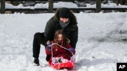 Una mujer juega con su hija en un trineo de nieve en el Parque Central de Nueva York el 13 de febrero de 2024.