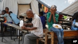 FILE—A man eats a meal as a child covers his face after receiving containers of free food at a shelter for families displaced by gang violence, in Port-au-Prince, Haiti, Thursday, March 14, 2024.