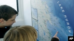 Estudiantes miran en un mapa del Lago Huron lugares donde hay buques hundidos en Thunder Bay National Marine Sanctuary.