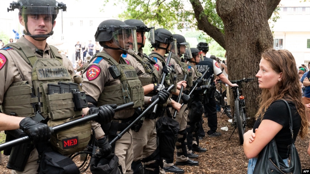 2024 年 4 月 24 日，德克萨斯州奥斯汀市的德克萨斯大学校园内，亲巴勒斯坦的学生抗议以色列与哈马斯的战争，一名学生静静地注视着一排德克萨斯州警察。(photo:VOA)