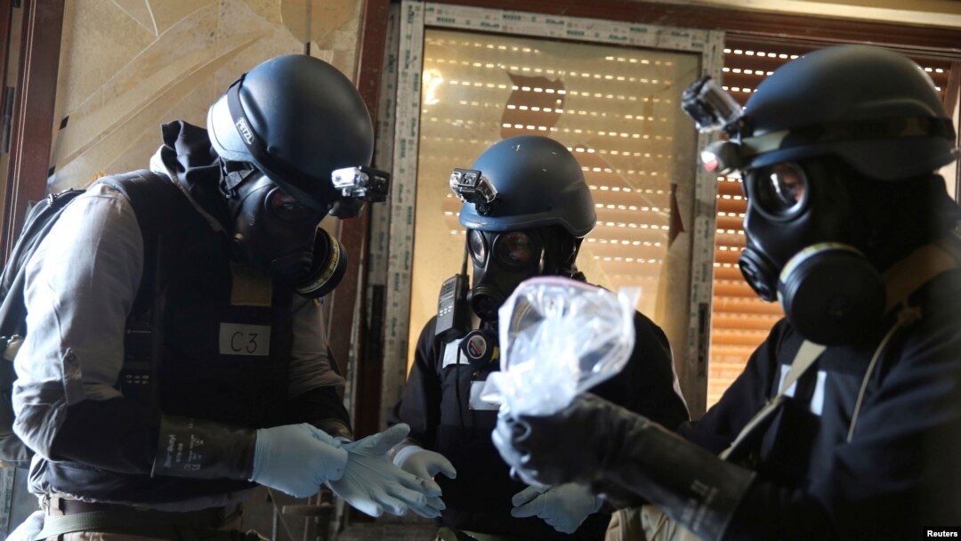 FILE - A U.N. chemical weapons expert, wearing a gas mask, holds a plastic bag containing samples from one of the sites of an alleged chemical weapons attack in the Ain Tarma neighborhood of Damascus, Syria, Aug. 29, 2013.