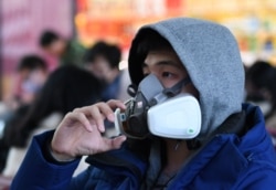 A passenger wearing a protective facemask to help stop the spread of a deadly SARS-like virus that originated in the central city of Wuhan waits at Beijing railway station in Beijing, Jan. 24, 2020.