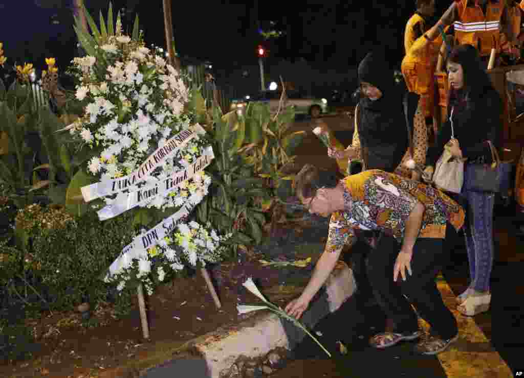 Indonesians lay flowers near the police post where an attack took place in the center of the Indonesian capital.