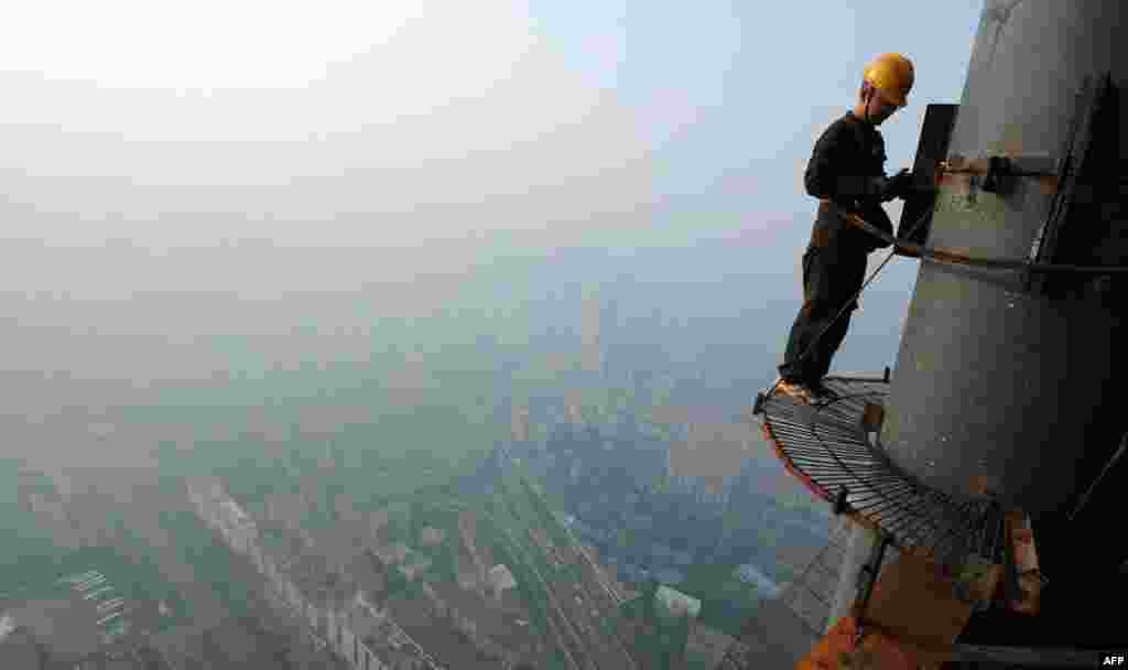 June 3: A labourer works on a steel structure at a financial building construction site, as the cityscape is seen amid smoke from burning straw, in Hefei, Anhui. (Reuters)