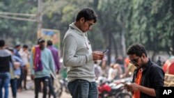 Ljudi koriste svoje mobilne telefone na području Univerziteta Daka, Bangladeš, 21. decembra 2023.