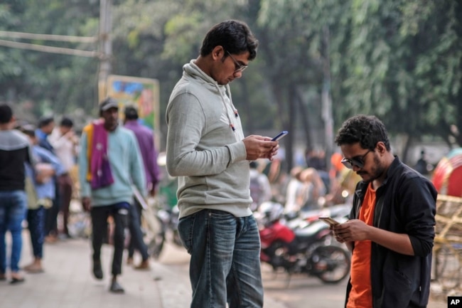 FILE - People engage with their mobile phones at Dhaka University area, Bangladesh, Dec.21, 2023. Artificial intelligence is supercharging the threat of election disinformation worldwide. (AP Photo/Mahmud Hossain Opu, File)