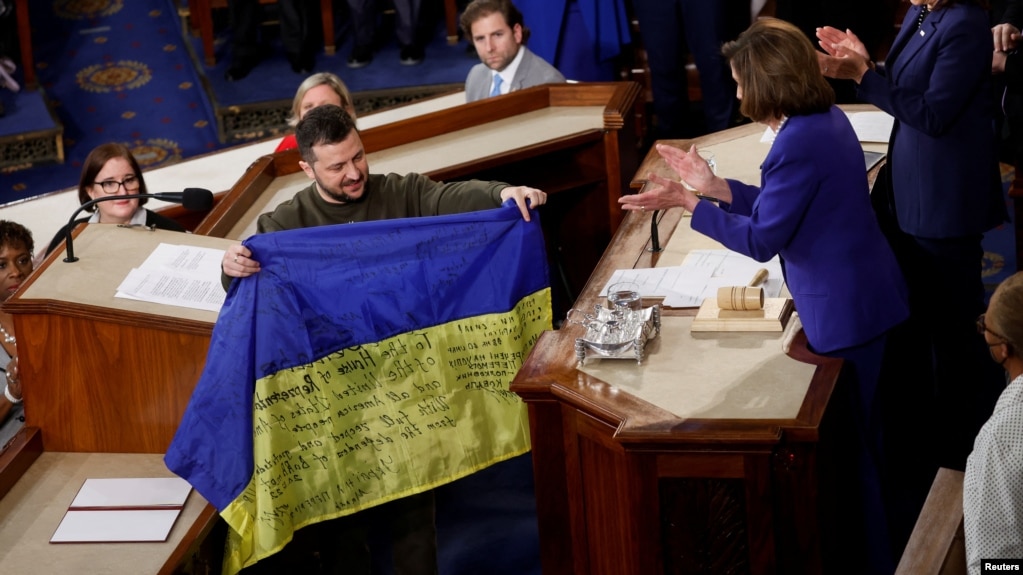 Ukraine's President Volodymyr Zelenskyy presents a Ukrainian flag given to him by defenders of Bakhmut to U.S. House Speaker Nancy Pelosi (D-CA) during a joint meeting of U.S. Congress in Washington, Dec. 21, 2022. 