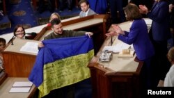 Ukraine's President Volodymyr Zelenskyy presents a Ukrainian flag given to him by defenders of Bakhmut to U.S. House Speaker Nancy Pelosi (D-CA) during a joint meeting of U.S. Congress in Washington, Dec. 21, 2022. 