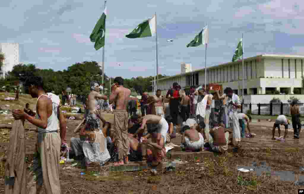 Pakistani protesters bathe at a leaking water supply line close to the parliament building, Islamabad, Sept. 2, 2014.