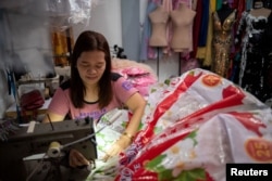 Leonora Buenviaje sews a dress out of used sacks of rice at her shop in Cainta in the Philippines on March 3, 2022. (REUTERS/Lisa Marie David)