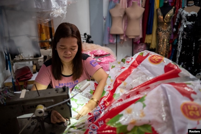 Leonora Buenviaje sews a dress out of used sacks of rice at her shop in Cainta in the Philippines on March 3, 2022. (REUTERS/Lisa Marie David)