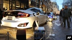 People look at Honda's new fuel cell vehicle "Clarity" that is distributing its hydrogen fuel cell power to illuminate six trees along the street in Tokyo's Marunouchi office and shopping district in Tokyo Friday, Dec. 25, 2015. (AP Photo/Koji Sasahara)