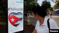 A woman passes by a screen displaying images promoting the vote for "yes" for the constitutional referendum, in Havana, Cuba, Feb. 5, 2019. 