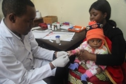 FILE - A doctor tests a child for malaria at the Ithani-Asheri Hospital in Arusha, Tanzania, May 11, 2016.