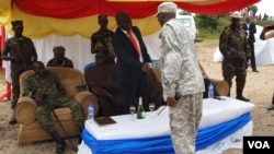 New president of the M23 rebel movement, Bertrand Bisimwa (in orange tie) shakes hands with M23 military commander Sultani Makenga, in Bunagana in eastern DRC, March 7, 2013. (N. Long/VOA)