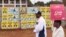 Duas pessoas passam por cartazes eleitorais colados numa parede em Kuwadzana, Harare