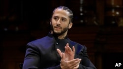 FILE - NFL football quarterback Colin Kaepernick applauds during W.E.B. Du Bois Medal ceremonies at Harvard University in Cambridge, Mass. 