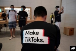 FILE - A man wearing a shirt promoting TikTok is seen at an Apple store in Beijing, China, July 17, 2020.