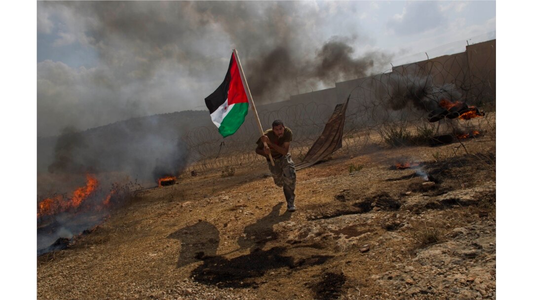 FILE - Palestinian Ashraf Abu Rahma runs away from tear gas fired by Israeli troops, not pictured, during a demonstration in the West Bank town of Bilin, near Ramallah, Sept. 9, 2011.