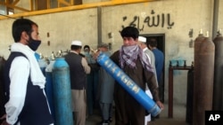 A man carries an oxygen tank from a privately owned oxygen factory in Kabul, Afghanistan, June 18, 2020. For seven years, Najibullah Seddiqi's oxygen factory sat idle. Now he refills hundreds of oxygen cylinders a day for free for COVID patients.