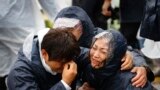 Family members of passengers missing on the overturned South Korean ferry Sewol react at the port in Jindo.