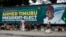 People sit under a billboard with a congratulatory message of the President-Elect Bola Ahmed Tinubu of the All Progressives Congress in Lagos, Nigeria, March 5, 2023.